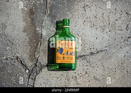 Eine leere Flasche Buckfast Tonic Wine, oder „Buckie“, wie er vor Ort bekannt ist, auf dem Bürgersteig in Edinburgh, Schottland, Großbritannien. Stockfoto