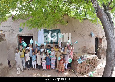 Lahore, Punjab, Pakistan. 12. August 2022. Die Kinder und Arbeiter der United Social Welfare Society von pakistanischen Ziegelöfen feiern den Unabhängigkeitstag 75. am Ziegelofen in Lahore. Der Unabhängigkeitstag (Y?um-e-?z?di), der jährlich am 14. August begangen wird, ist ein Nationalfeiertag in Pakistan. Es erinnert an den Tag, an dem Pakistan seine Unabhängigkeit erlangte und nach dem Ende des britischen Raj im Jahr 1947 zum souveränen Staat erklärt wurde. Pakistan entstand durch die Pakistan-Bewegung, die auf die Schaffung eines unabhängigen muslimischen Staates in den nordwestlichen Regionen abzielte Stockfoto