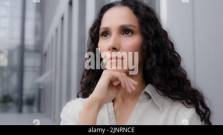 Nahaufnahme nachdenklich nachdenklich verwirrt kaukasischen hispanischen nachdenklich Mädchen Frau mit lockigen Haaren im Freien stehen traurig Sorgen träumen Planung Stockfoto