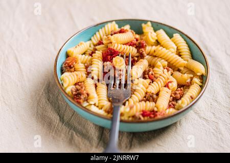 Bolognese Pasta in blauer Platte auf hellem Hintergrund. Traditionelles italienisches Gericht Stockfoto