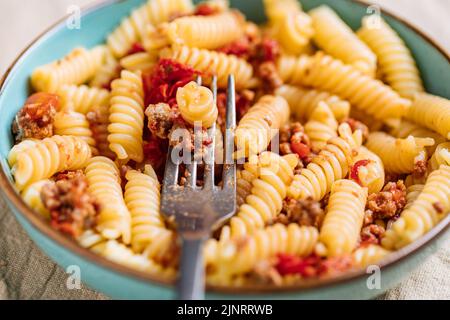 Bolognese Pasta in blauer Platte auf hellem Hintergrund. Traditionelles italienisches Gericht Stockfoto