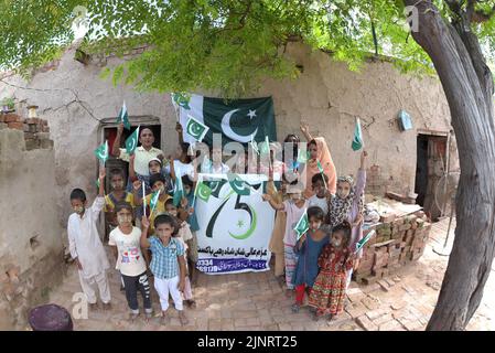 Lahore, Punjab, Pakistan. 12. August 2022. Die Kinder und Arbeiter der United Social Welfare Society von pakistanischen Ziegelöfen feiern den Unabhängigkeitstag 75. am Ziegelofen in Lahore. Der Unabhängigkeitstag (Y?um-e-?z?di), der jährlich am 14. August begangen wird, ist ein Nationalfeiertag in Pakistan. Es erinnert an den Tag, an dem Pakistan seine Unabhängigkeit erlangte und nach dem Ende des britischen Raj im Jahr 1947 zum souveränen Staat erklärt wurde. Pakistan entstand durch die Pakistan-Bewegung, die auf die Schaffung eines unabhängigen muslimischen Staates in den nordwestlichen Regionen abzielte Stockfoto