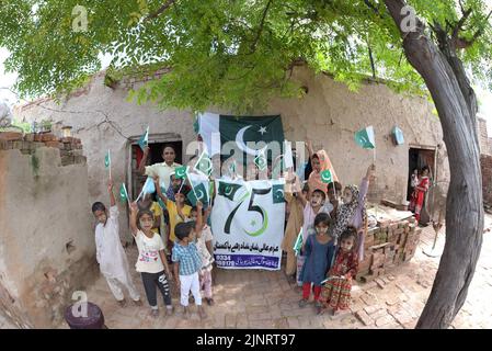 Lahore, Punjab, Pakistan. 12. August 2022. Die Kinder und Arbeiter der United Social Welfare Society von pakistanischen Ziegelöfen feiern den Unabhängigkeitstag 75. am Ziegelofen in Lahore. Der Unabhängigkeitstag (Y?um-e-?z?di), der jährlich am 14. August begangen wird, ist ein Nationalfeiertag in Pakistan. Es erinnert an den Tag, an dem Pakistan seine Unabhängigkeit erlangte und nach dem Ende des britischen Raj im Jahr 1947 zum souveränen Staat erklärt wurde. Pakistan entstand durch die Pakistan-Bewegung, die auf die Schaffung eines unabhängigen muslimischen Staates in den nordwestlichen Regionen abzielte Stockfoto