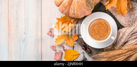 Herbsthintergrund mit Kaffeebecher, Kürbis und Herbstlaub auf einem heiligen Holzhintergrund. Stockfoto