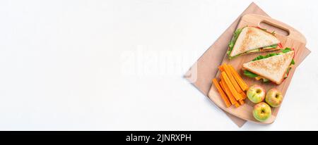 Sandwich, Äpfel und Karotten auf grauem Hintergrund Stockfoto