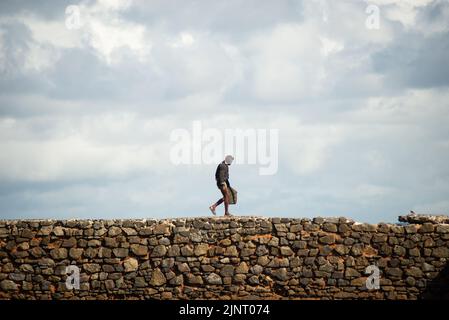 Salvador, Bahia, Brasilien - 04. Juni 2022: Die Menschen wandern auf dem steinernen Wellenbrecher des Strandes Porto da Barra in Salvador, Bahia. Stockfoto