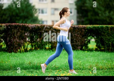 Tanktop und Leggings auf jungen Joggern im öffentlichen Park. Stockfoto