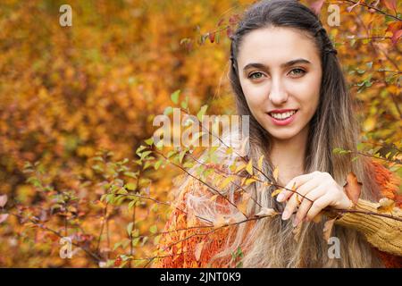 Hübsches Mädchen auf Herbst orange Hintergrund. Junge Frau mit langen Haaren. Hochformat Stockfoto