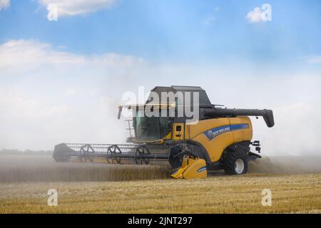 Mähdrescher mit der Flagge der ukraine erntet Weizen auf dem Feld in der Region Dnipro, Ukraine. 8. August 2022 Stockfoto