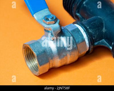 Wasserventil auf orangefarbenem Hintergrund. Bewässerungskonzept Stockfoto