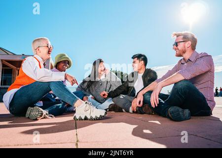 Eine Gruppe von Freunden, die auf dem Boden sitzen, lachen und Spaß haben. Stockfoto