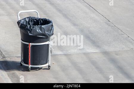 Auf einer sonnigen Straße steht ein mobiler Abfalleimer auf Rädern Stockfoto