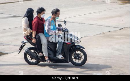 SAMUT PRAKAN, THAILAND, MAI 28 2022, Ein Taxifahrer auf einem Motorrad fährt mit einem Paar. Stockfoto