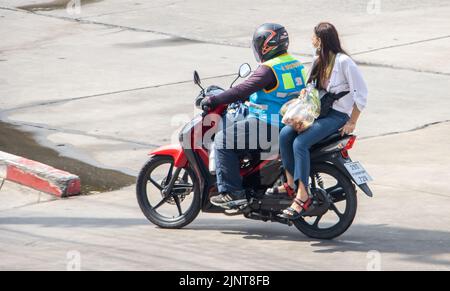 SAMUT PRAKAN, THAILAND, MAI 28 2022, Ein Taxifahrer auf einem Motorrad fährt mit einer Frau. Stockfoto