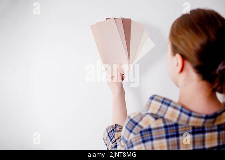 Die junge Frau hält Farbproben für die Wand in der Hand Stockfoto