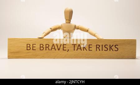 Seien Sie mutig, gehen Sie Risiken ein, die auf der Holzoberfläche geschrieben sind. Motivation und persönliche Entwicklung. Stockfoto