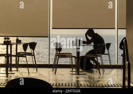 Tel Aviv, Israel. 10. August 2022. Ein Mann, der während des Sonnenuntergangs in Tel Aviv in einem Kaffeehaus gesehen wurde. Tel Aviv, das sich an der Mittelmeerküste befindet, ist Israels kulturelles Zentrum und ein wichtiges Reiseziel, das Touristen aus der ganzen Welt anzieht. (Bild: © Ronen Tivony/SOPA Images via ZUMA Press Wire) Stockfoto