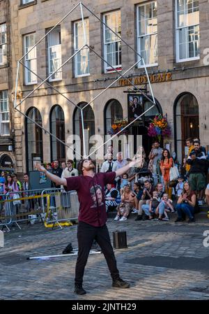 Edinburgh, Schottland, Großbritannien, 13.. August 2022. Edinburgh Fringe Unterhaltung: Ein Straßenkünstler unterhält die Menge mit einem Balanceakt Stockfoto