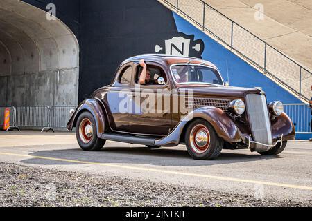 Libanon, TN - 14. Mai 2022: Weitwinkelansicht eines Ford Five Window Coupés aus dem Jahr 1935, das auf einer Straße fährt, die eine lokale Automobilausstellung verlässt. Stockfoto