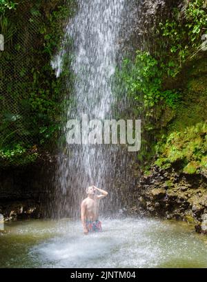 Junge Männer entspannen sich am Toraille Wasserfall St. Lucia. St. Lucia Dschungel Wasserfall und Männer schwimmen. Toraille Falls Sain Lucia Stockfoto