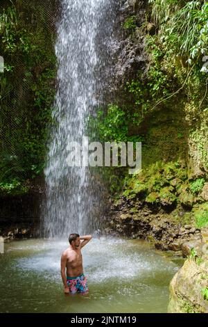 Junge Männer entspannen sich am Toraille Wasserfall St. Lucia. St. Lucia Dschungel Wasserfall und Männer schwimmen. Toraille Falls Sain Lucia Stockfoto