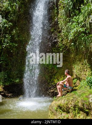 Junge Männer entspannen sich am Toraille Wasserfall St. Lucia. St. Lucia Dschungel Wasserfall und Männer schwimmen. Toraille Falls Sain Lucia Stockfoto