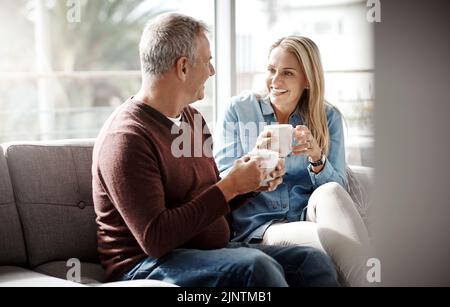 Date Night aus dem Komfort von zu Hause. Ein reifes Paar genießt eine entspannende Kaffeepause auf dem Sofa zusammen zu Hause. Stockfoto