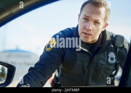 Du fragst dich wahrscheinlich, warum ich dich herübergezogen habe... ein hübscher junger Mann, der an einer Straßensperre arbeitet. Stockfoto