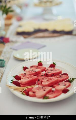 Tee-Party-Snacks können auch gesund sein. Wassermelone in Herzformen auf einem Tisch auf einer Tee-Party im Inneren geschnitten. Stockfoto