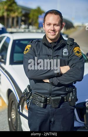 Ich arbeite mich bis zum Detektiv. Ein beschnittenes Porträt eines hübschen jungen Polizisten, der mit gekreuzten Armen auf der Patrouille steht. Stockfoto