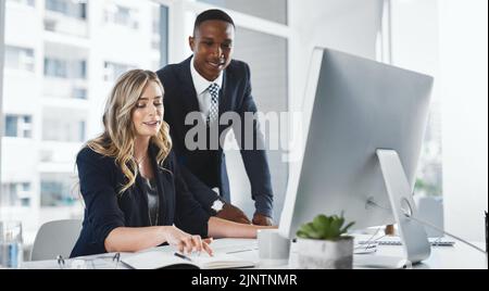 Betrachten Sie jede wichtige Information, bevor Sie Entscheidungen treffen. Zwei Geschäftsleute, die in einem Büro zusammenarbeiten. Stockfoto