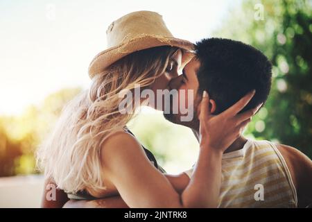 Alles, was sie will, ist sein Kuss auf ihre Lippen. Ein liebevolles junges Paar, das einen intimen Moment draußen auf ihrem Balkon teilt. Stockfoto