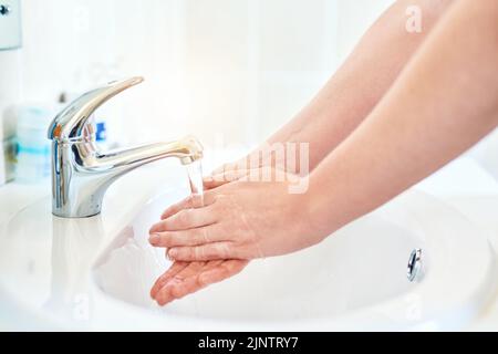 Jeder Tropfen zählt. Nahaufnahme einer unkenntlichen Frau, die sich im Waschbecken im Badezimmer zu Hause die Hände wascht. Stockfoto