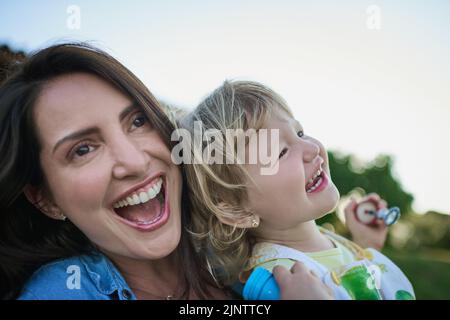 Eine Mutter und ihre kleine Tochter blasen im Freien. Stockfoto