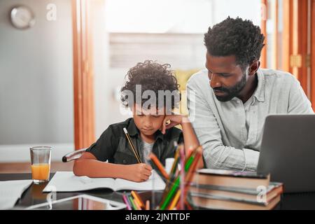 Finden Sie die Zeit, um Ihre Kinder zu unterstützen und zu ermutigen. Ein Mann hilft seinem Sohn bei seinen Hausaufgaben. Stockfoto