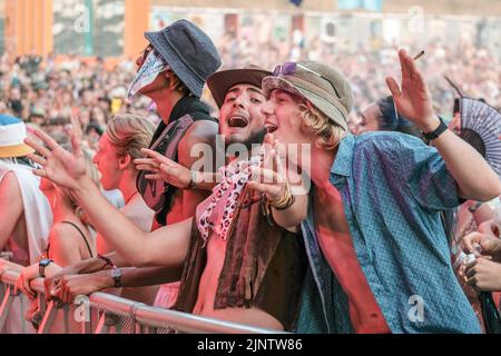 Viele Jugendliche in Kostümen sahen auf dem Fair Festival singen und tanzen. Boomtown Festival - Kapitel 1: The Gathering - findet im Matterley Estate, in der Nähe von Winchester, Hampshire, statt und wird von Mittwoch, 10.. Bis Sonntag, 14.. August 2022, stattfinden. Boomtown folgt einer Geschichte, die sich jedes Jahr entwickelt und für die Welt nach der Pandemie zurückgesetzt wurde, in der der Ausnahmezustand zu einem Zustand des Aufbruchs wurde, der aus der Asche des Alten auferstanden ist. Es ist eine neue Welt, begleitet von einer neuen Geschichte, die darauf wartet, erzählt zu werden, die sich auf Reflexion, Akzeptanz und Wiederverbindung konzentriert. Es ist eine Zeit von Stockfoto