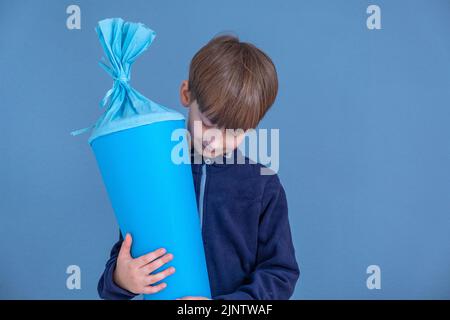 Kind hält am ersten Schultag traditionellen deutschen Süßigkeitenkegel. Junge mit einer süßen Tasche. Schulbeginn in Deutschland Stockfoto