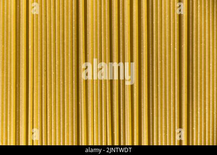 Italienische gesunde Lebensmittel Hintergrund, rohe Spinat Spaghetti füllen den Rahmen in einem strukturierten Design aus grünen vertikalen Pasta-Linien. Stockfoto