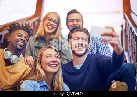 Diese werden zu deinen Freunden fürs Leben. Eine Gruppe von verschiedenen Studenten, die ein Selfie auf der Treppe auf dem Campus machen. Stockfoto