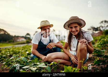 Väter lehren mich alles, was ich wissen muss. Ganzkörperportrait eines gutaussehenden Mannes und seiner jungen Tochter, die auf ihrem Bauernhof auf den Feldern arbeiten. Stockfoto