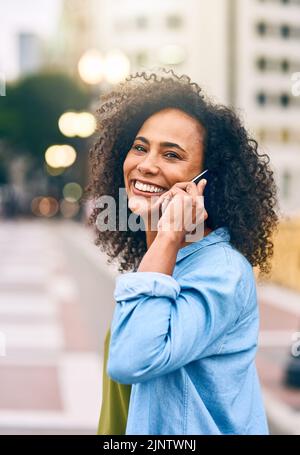 Auf dem Weg zu einem Mittagessen in der Stadt. Eine junge Frau benutzt ihr Handy, während sie in der Stadt unterwegs ist. Stockfoto