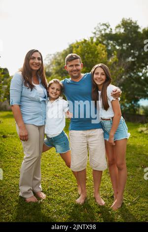 Sie sind eine Bilderbuchfamilie. Ganzkörperportrait einer jungen vierköpfigen Familie, die draußen steht. Stockfoto