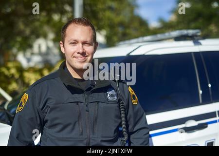 Ich habe einen guten Tag im Patrouillendienst. Beschnittenes Porträt eines hübschen jungen Polizisten auf Patrouille. Stockfoto