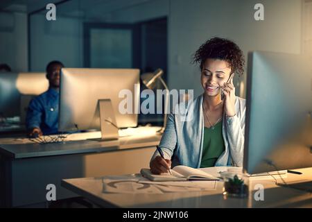 Er ist ein Profi, wenn es um die Verwaltung mehrerer Aufgaben geht: Eine junge Geschäftsfrau, die spät in einem Büro arbeitet. Stockfoto