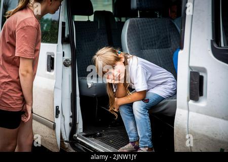 Kurdiumiwka, Oblast Donezk, Ukraine. 4. August 2022. Tanya (7 Jahre) und ihre Familie sahen in Kurdiumivka, Donbas, auf die Evakuierung warten. Die Zeit läuft, und Freiwillige aus der Ukraine, aber auch aus der ganzen Welt Rennen mit der Zeit, um die Menschen zu evakuieren, die bereit sind, von der Ostfront zu gehen, da ihre Häuser während der verstärkten Kämpfe im östlichen Teil der Ukraine zerstört wurden, Millionen ukrainischer Familien sind nun aus dem immer näher rückt Krieg evakuiert worden, da viele von ihnen in den westlichen Teil des Landes verlegt werden. Nach Angaben der Vereinten Nationen, mindestens 12 Stockfoto