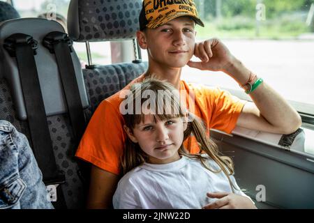 Kurdiumiwka, Oblast Donezk, Ukraine. 4. August 2022. Tanya (7 Jahre) und Bruder Zhenya (14 Jahre) evakuieren aus der Stadt Kurdiumiwka nach Kramatorsk, Donbas, wo sie später nach Dnipro verlegt werden. Die Zeit läuft, und Freiwillige aus der Ukraine, aber auch aus der ganzen Welt Rennen mit der Zeit, um die Menschen zu evakuieren, die bereit sind, von der Ostfront zu gehen, da ihre Häuser während der verstärkten Kämpfe im östlichen Teil der Ukraine zerstört wurden, Millionen ukrainischer Familien sind nun aus dem immer näher rückt Krieg evakuiert worden, da viele von ihnen in den verlagert werden Stockfoto