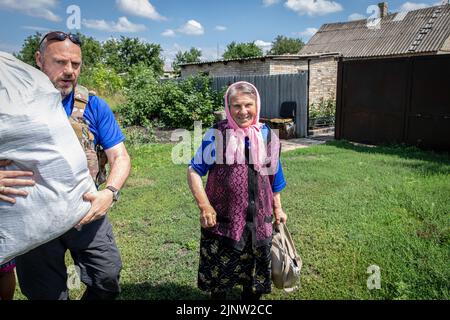 Kurdiumiwka, Oblast Donezk, Ukraine. 4. August 2022. Ein Freiwilliger aus Großbritannien sah, wie er einer alten Dame half, in das Evakuierungsfahrzeug in Kurdiumivka, Donbas, zu steigen. Die Zeit läuft, und Freiwillige aus der Ukraine, aber auch aus der ganzen Welt Rennen mit der Zeit, um die Menschen zu evakuieren, die bereit sind, von der Ostfront zu gehen, da ihre Häuser während der verstärkten Kämpfe im östlichen Teil der Ukraine zerstört wurden, Millionen ukrainischer Familien sind nun aus dem immer näher rückt Krieg evakuiert worden, da viele von ihnen in den westlichen Teil des Landes verlegt werden. Nach Angaben der Vereinten Nationen Stockfoto