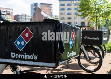 Domino's Pizza Delivery Bikes stehen in der Schlange, bereit für die Zusteller, um den Kunden frisch gebackene Pizza zu liefern. Stockfoto