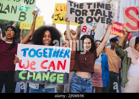 Jugend protestiert gegen den Klimawandel. Gruppe multikultureller Jugendaktivisten, die Plakate und Banner tragen, während sie gegen die globale Erwärmung marschieren. Glücklich Stockfoto