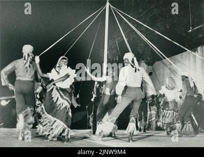 Schwarz-Weiß-Fotografie von Menschen in Kostümen, die um einen Maibaum in Barbados, Westindien, tanzen Stockfoto